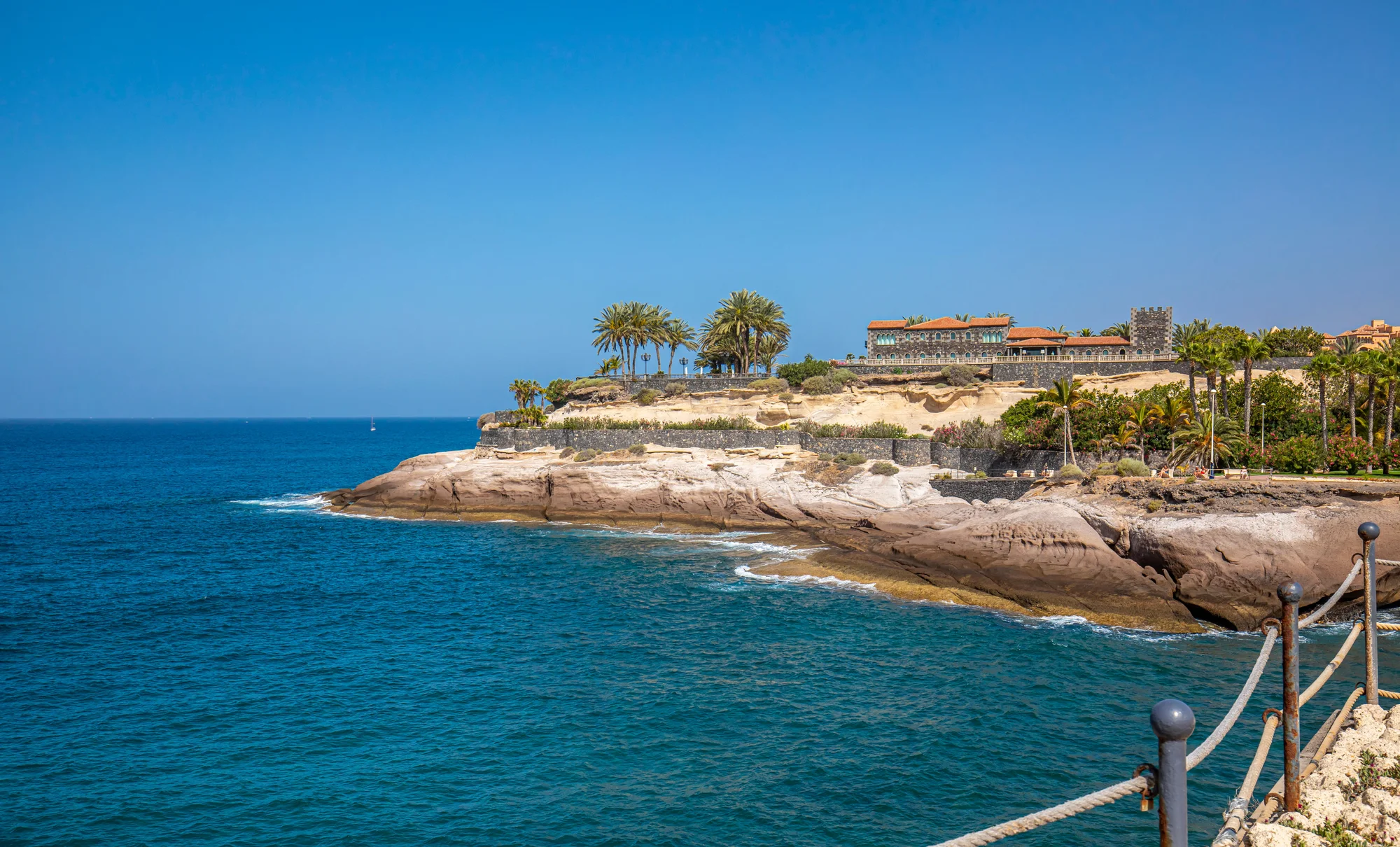 De kust bij Costa Adeje, met de Atlantische Oceaan, lichte rotsen en palmen