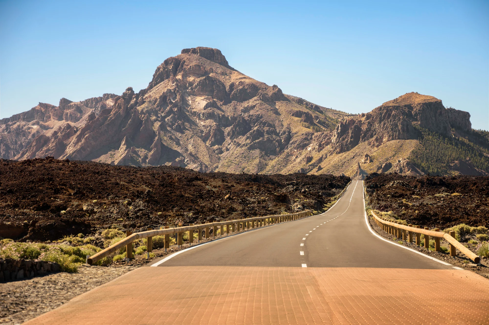 Una carretera entre campos de lava oscura hacia las montañas